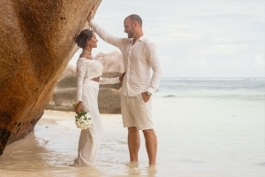 Hochzeit La Digue ganz in Weiss - Brautpaar lehnt am Felsen Hochzeit La Digue ganz in Weiss - Brautpaar lehnt am Felsen