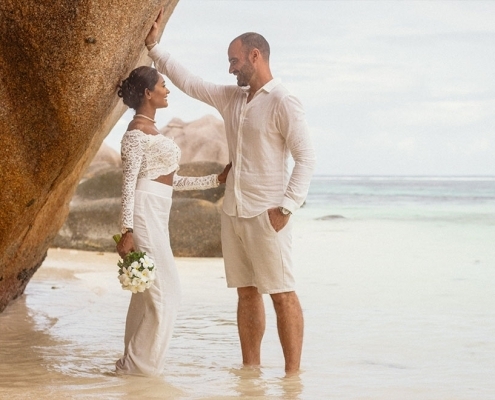 Hochzeit La Digue ganz in Weiss - Brautpaar lehnt am Felsen Hochzeit La Digue ganz in Weiss - Brautpaar lehnt am Felsen