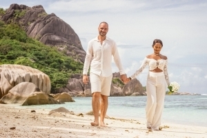 Hochzeit La Digue ganz in Weiss mit eine Glas Sekt anstossen Brautpaar vor Felsenkulisse Hochzeit La Digue ganz in Weiss mit eine Glas Sekt anstossen Brautpaar vor Felsenkulisse