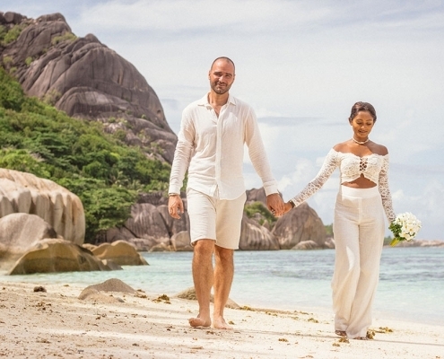 Hochzeit La Digue ganz in Weiss mit eine Glas Sekt anstossen Brautpaar vor Felsenkulisse Hochzeit La Digue ganz in Weiss mit eine Glas Sekt anstossen Brautpaar vor Felsenkulisse